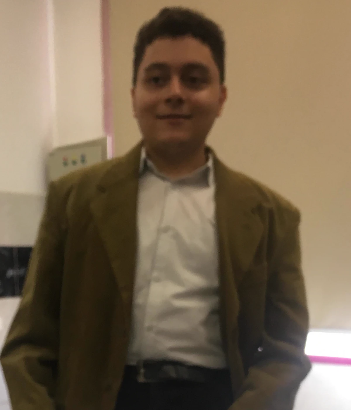 Mohamed Eassa in an olive blazer, holding printouts in an office corridor